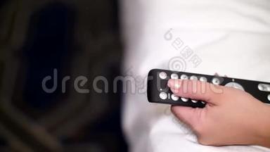 特写，一只雌手握着电视的<strong>遥控</strong>器，按下按钮，切换频道.. 看电视和使用<strong>遥控</strong>器